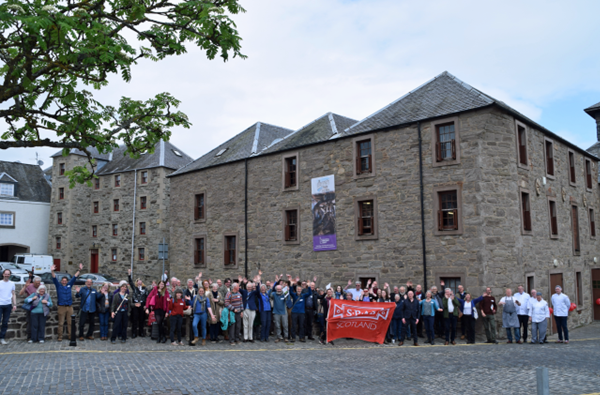 A group of SPAB Scotland Mills Weekend delegates cheering outside a mill.