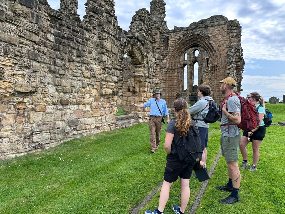 A group of people looking at a ruined abbey 