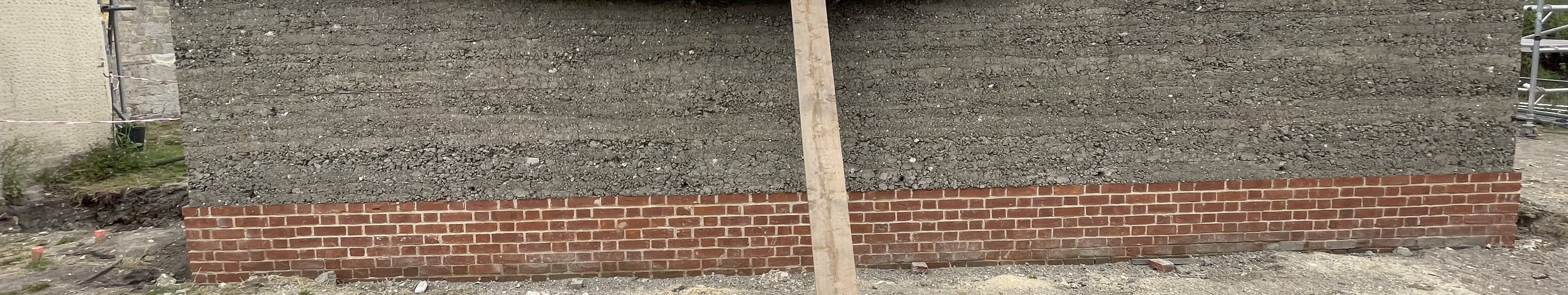Rammed earth wall with brick plinth at St Andrew's Chapel