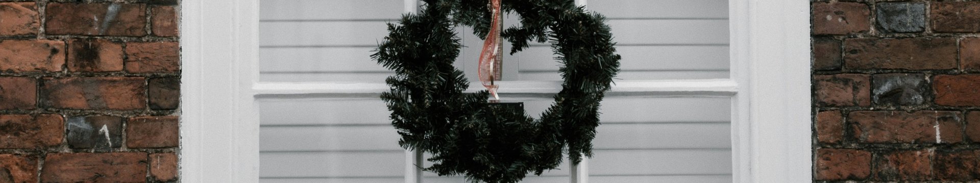 Photograph of sash window with Christmas wreath hanging from it.