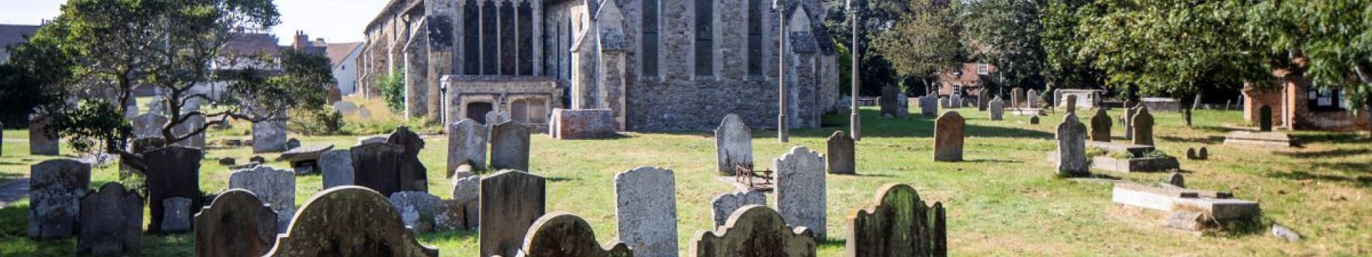 Lydd All Saints Church with the graveyard in the foreground. Sunny weather