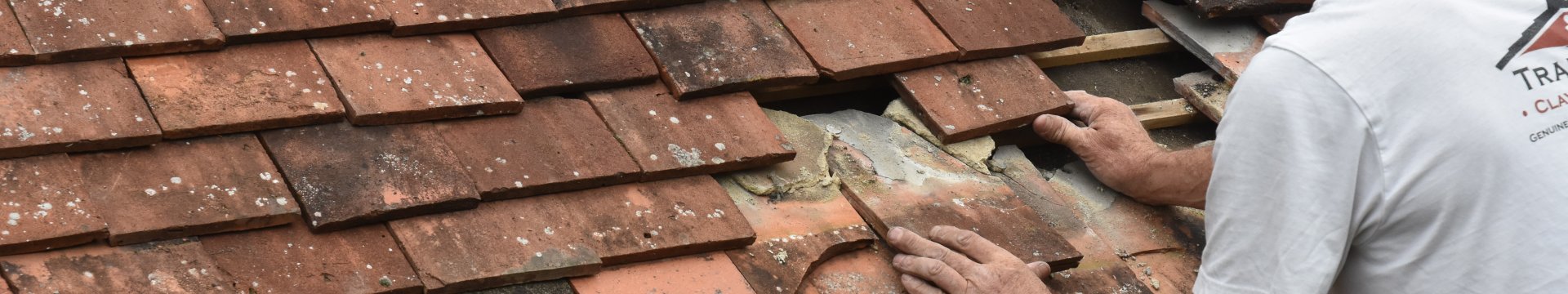 A man works to repair broken roof tiles