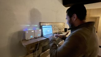 Jason Ratcliffe setting up the monitoring. Working on a laptop with other gadgets on a shelf