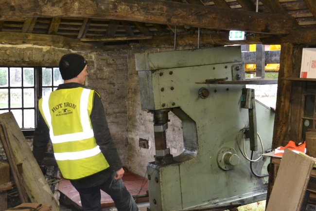 A power hammer machine being delivered through and old doorway. A man in a high-vis vest in the foreground