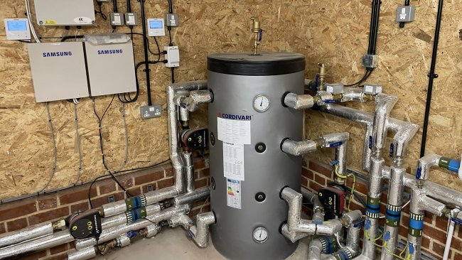 The Air Source Heat Pump water tank with connected pipes and controls 