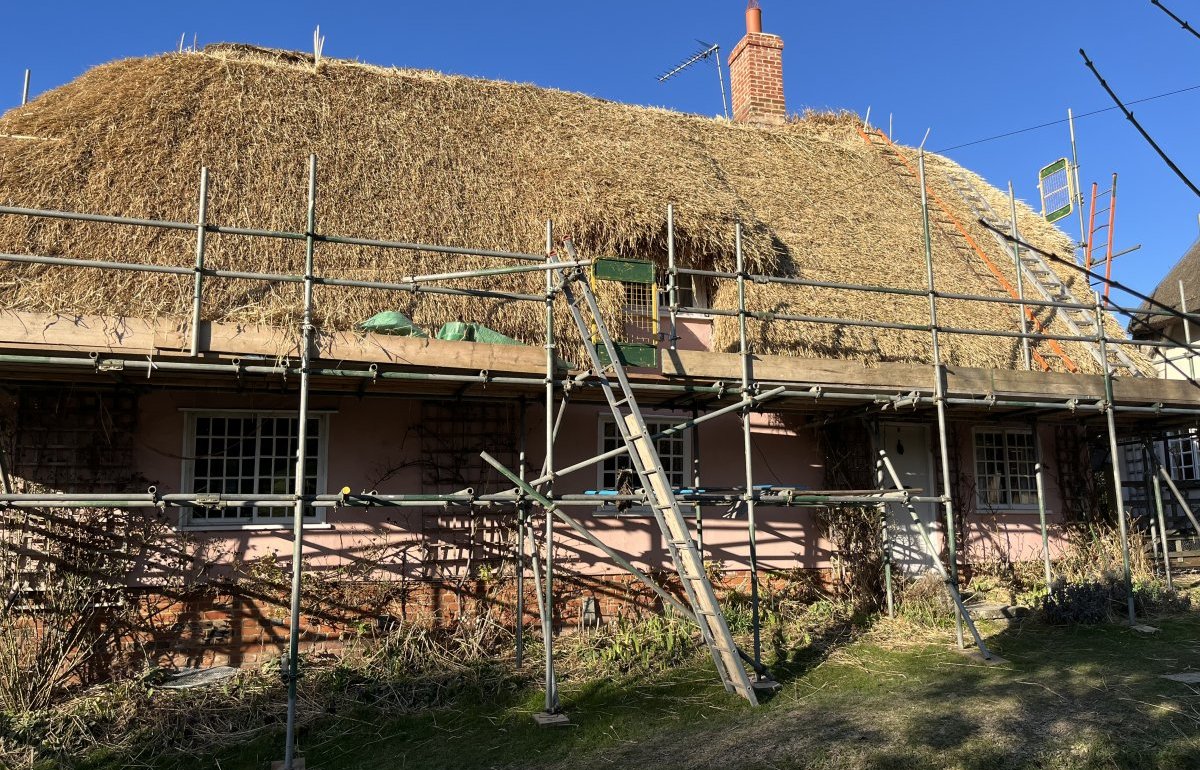 A thatched building with scaffolding up during the rethatching